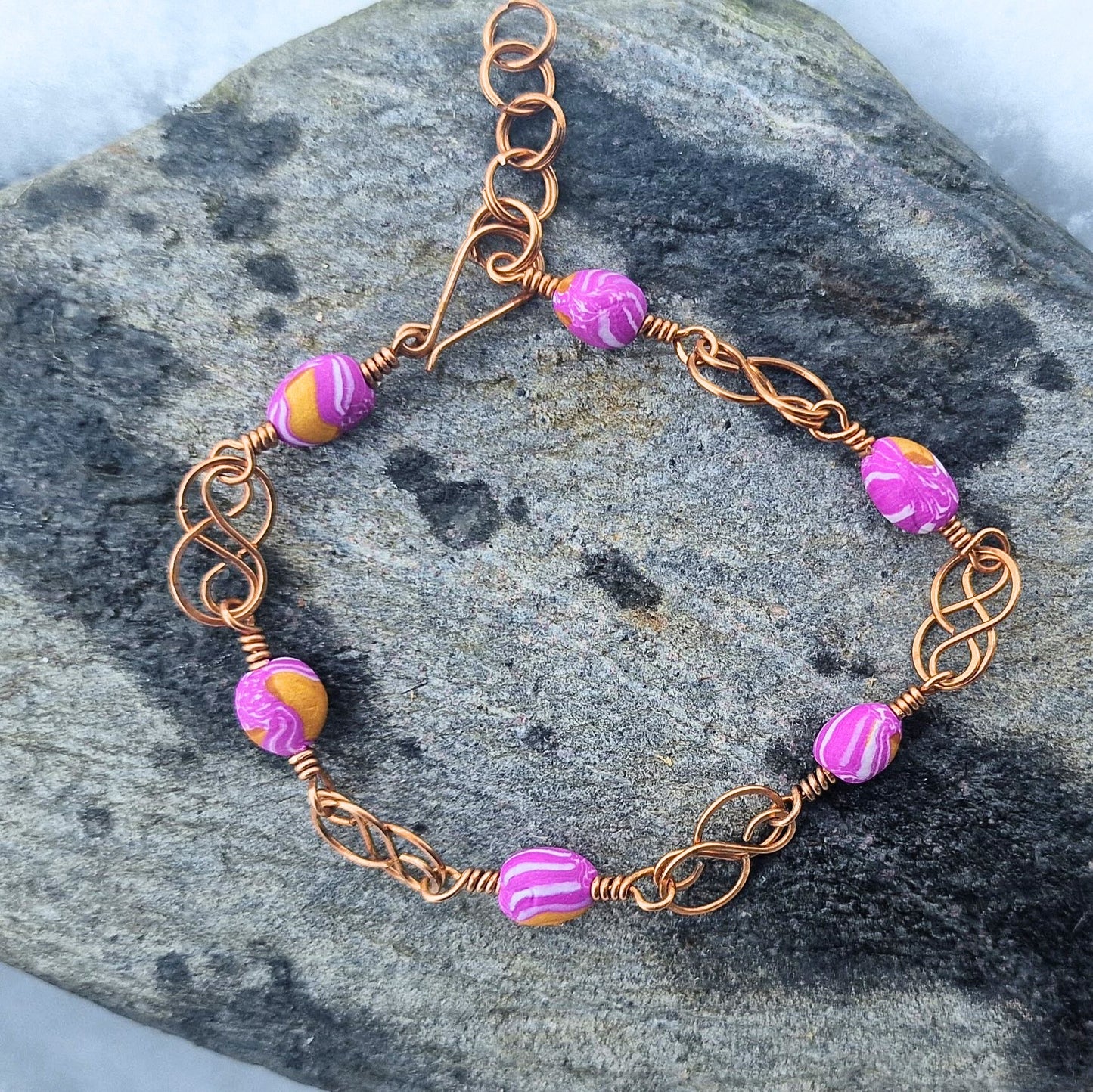 Armbånd med keltisk inspirert design i bronse og rosa polymer perler