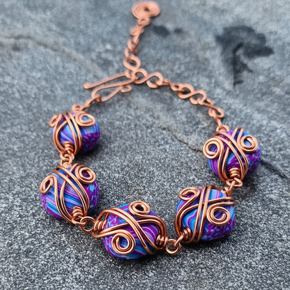 Armbånd med dekorativ kobbertvinning og håndlagde perler i lilla og turkis
