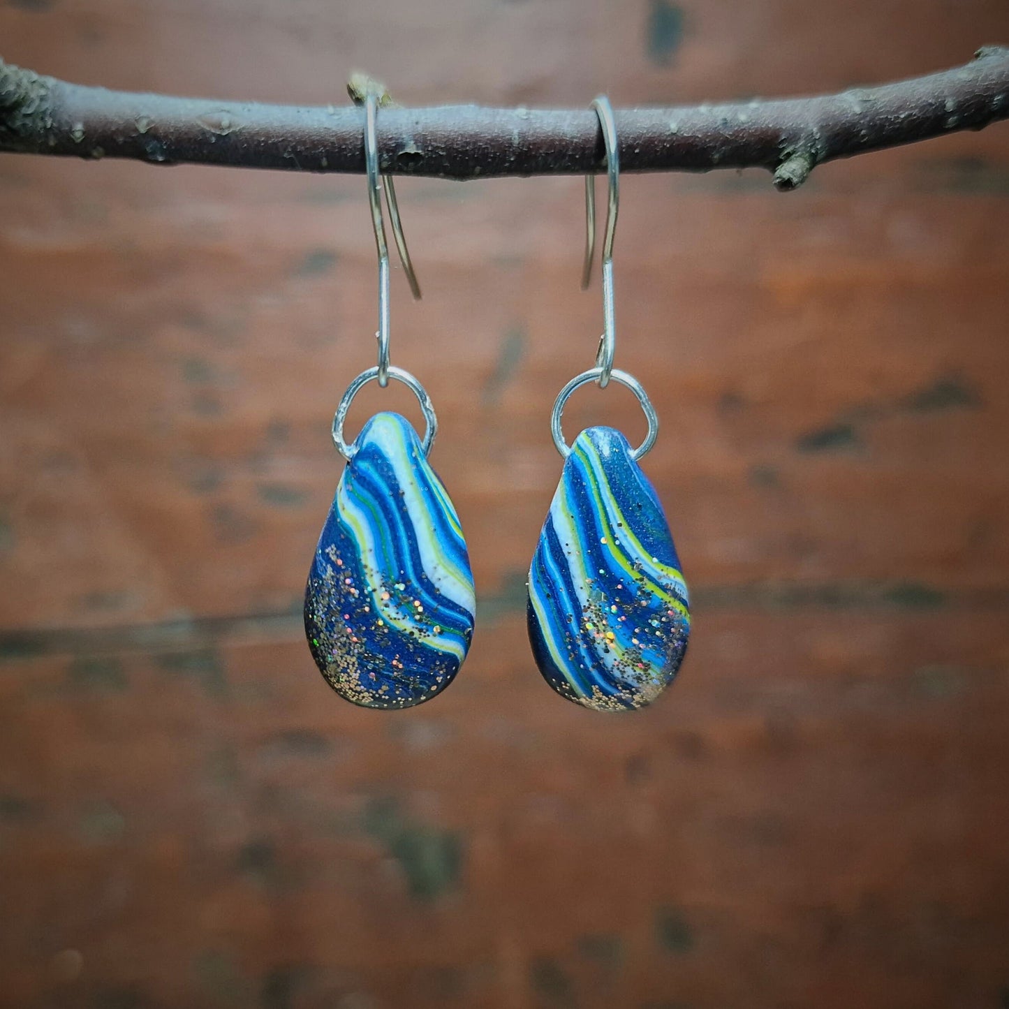 Stripete øredobber med stiper i blått, hvitt og gult med ett hint av glitter