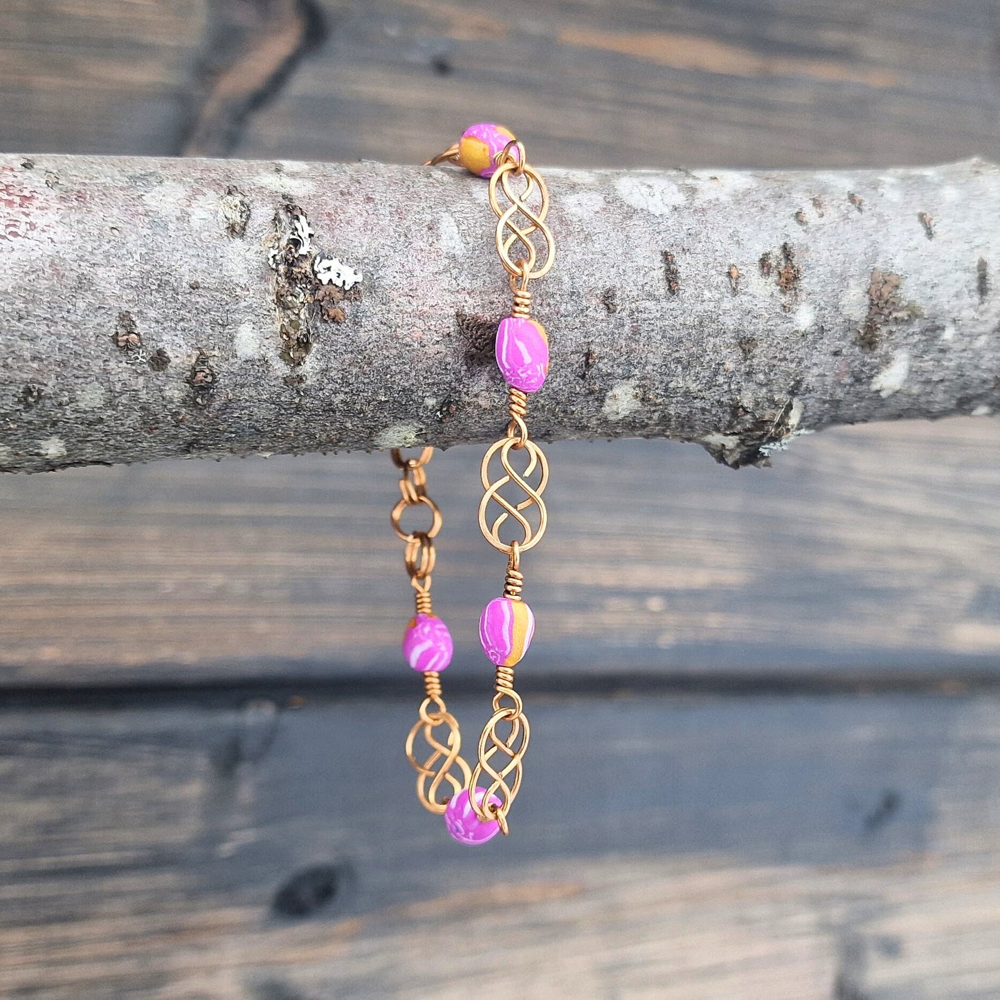 Armbånd med keltisk inspirert design i bronse og rosa polymer perler