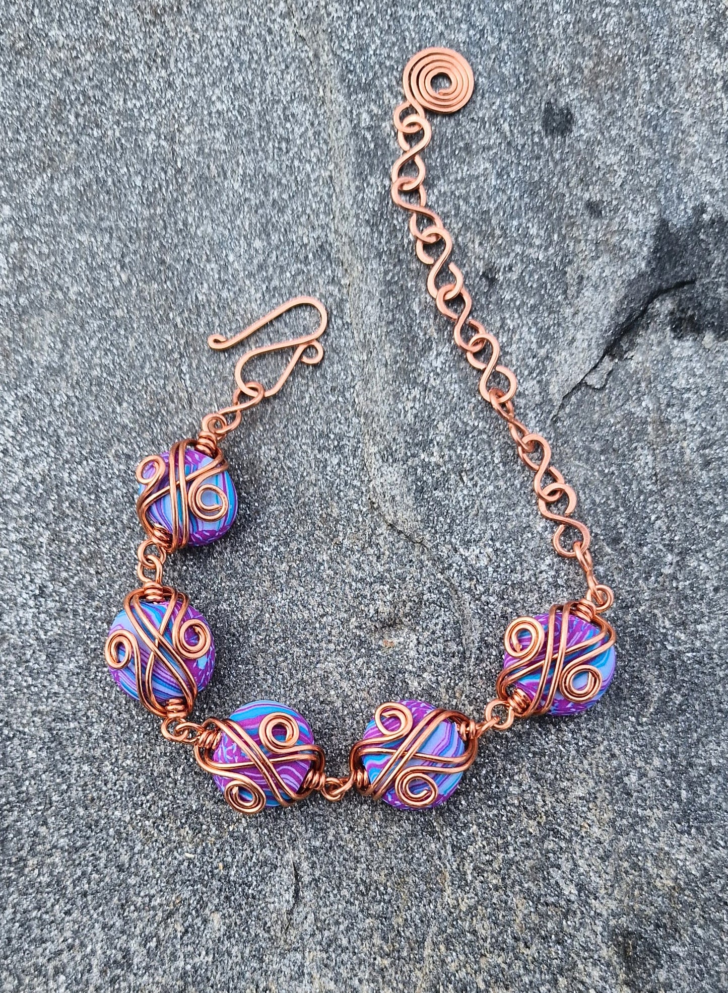 Armbånd med dekorativ kobbertvinning og håndlagde perler i lilla og turkis